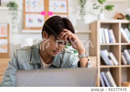 Stressed Asian man suffering from a strong migraine squeezing his head. Serious man have a headache with problem of him work. eye pain problem 92277470