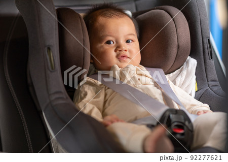 Smiling cute baby sit in car seat and secure with safety belts. Happy Asian infant baby sit in baby seat on car and looking around in car comfort and cheerful. Baby safety on car seat concept 92277621