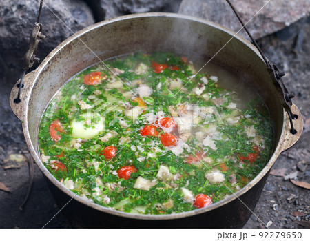 Freshly cooked hot soup in sooty cauldron at camping Freshly cooked hot soup in sooty cauldron at camping 92279650