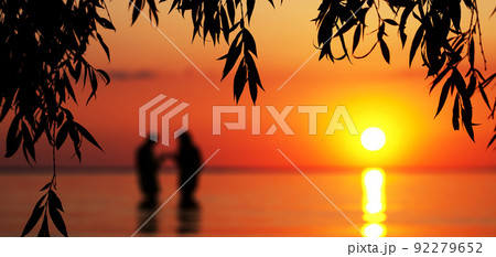 Blurred silhouette of young couple in love, standing in the sea at sunset 92279652