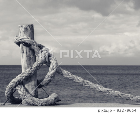Old rope on seafront, sea and cloudy sky 92279654