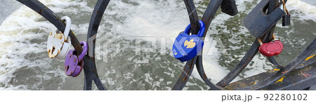 Wedding lock in soft focus as a symbol of love, tenderness, romance, eternity and endless love for lovers. Padlocks are attached to the bridge railing to celebrate the wedding, love locks Wedding lock in soft focus as a symbol of love, tenderness, romance, eternity and endless love for lovers. Padlocks are attached to the bridge railing to celebrate the wedding, love locks 92280102
