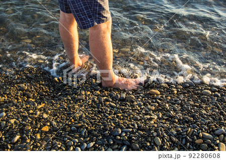 man walking alone on the pebble beach in the sunset man walking alone on the pebble beach in the sunset 92280608