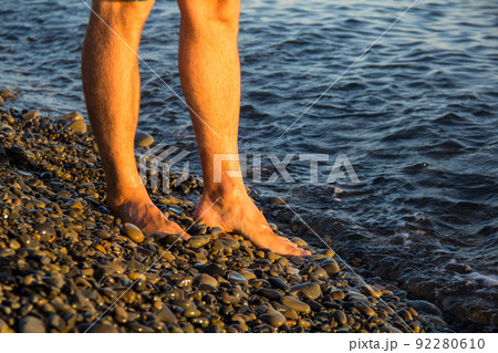 man walking alone on the pebble beach in the sunset man walking alone on the pebble beach in the sunset 92280610