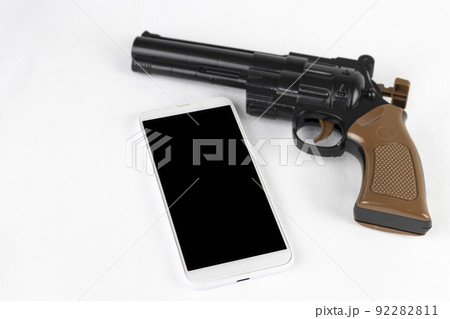 玩具の銃と、スマートフォン。犯罪予告のイメージ 92282811