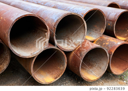 A group of Rusty metal pipes lying on the ground. Close-up, selective focus 92283639