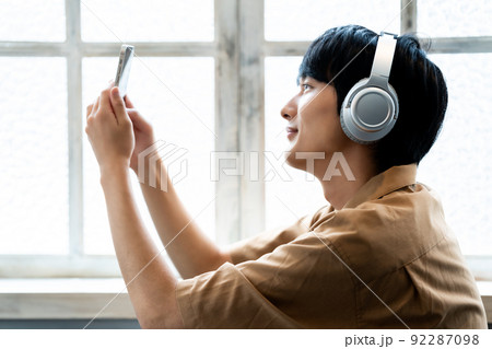 ヘッドフォンでスマホの音楽を聴く若い男性 92287098
