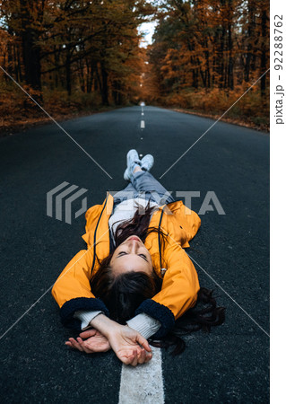 Confidence woman lying on the road with autumn tree around. New life, path choice, ambition, direction Confidence woman lying on the road with autumn tree around. New life, path choice, ambition, direction 92288762