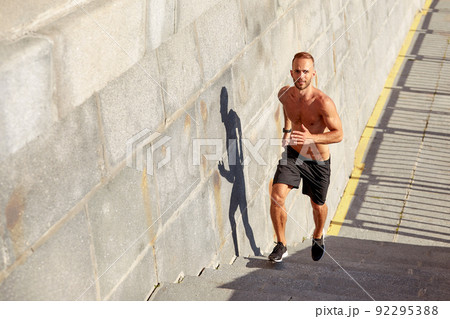 Young athlete man do morning run. Male runs up the stairs doing cardio exercises. 92295388