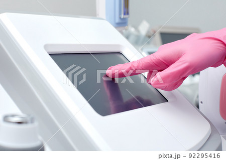 Doctor cosmetologist adjusts the device for photorejuvenation using the touchscreen 92295416
