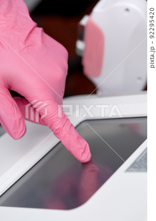 Doctor cosmetologist adjusts the device for photorejuvenation using the touchscreen 92295420