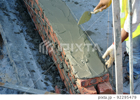 SELANGOR, MALAYSIA -MARCH 5, 2022: Brick installation works at construction sites. Bricks are installed in layers and joined with cement mortar. 92295479