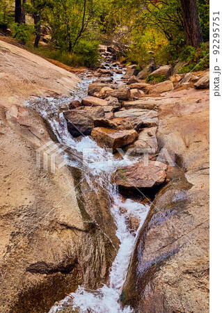 Small flowing water creek through rock canyon in forest 92295751