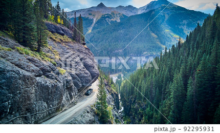 Dangerous dirt road with overhanging rocks next to cliff edge in valley of mountains 92295931