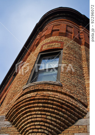Brick building with a rounded window jutting out of a corner 92296072
