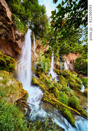 Vertical of large waterfalls over cliffs into lush green plants Vertical of large waterfalls over cliffs into lush green plants 92296095