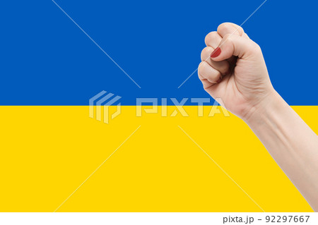 Woman hands with fist gesture on Ukraine flag color background Woman hands with fist gesture on Ukraine flag color background 92297667