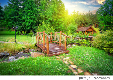 Wooden bridge over stream in green garden 92298829