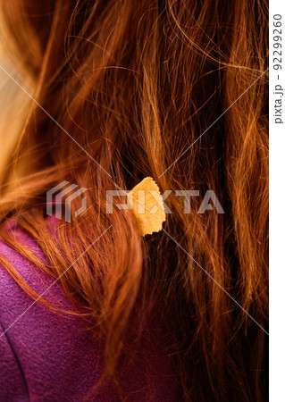 Autumn portrait of candid beautiful red-haired girl with fall leaves in hair. 92299260