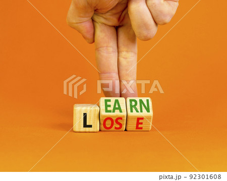 Learn or lose symbol. Concept words Learn and Lose on wooden cubes. Businessman hand. Beautiful orange table orange background. Business and Learn or Lose concept. Copy space. 92301608
