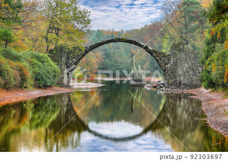 Fabulous autumn landscape in Azalea and Rhododendron Park Kromlau. Rakotz Bridge (Rakotzbrucke, Devil's Bridge) Fabulous autumn landscape in Azalea and Rhododendron Park Kromlau. Rakotz Bridge (Rakotzbrucke, Devil's Bridge) 92303697
