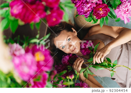 an attractive woman on the floor with a bouquet of peonies. an attractive woman on the floor with a bouquet of peonies. 92304454