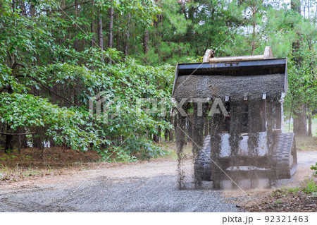 There is a Bobcat tractor moving and unloading gravel on an old road reconstruction project 92321463