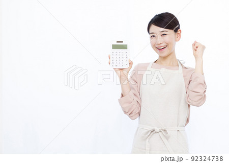 電卓を持ちガッツポーズをしている30代の主婦 電卓を持ちガッツポーズをしている30代の主婦 92324738