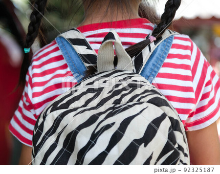 Rear view of happy smiling little girl with backpack getting in the car to ride to school. Little girl is happy and ready to learn. Back to school. 92325187