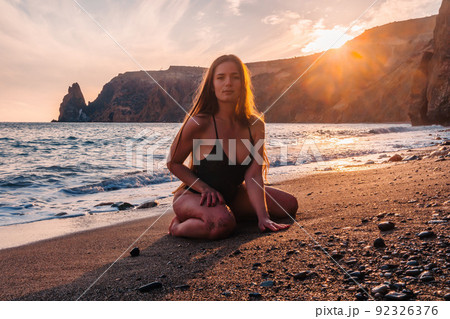 Selective focus. Happy carefree sensual woman with long hair in black swimwear posing at sunset beach. Silhouette of young beautiful playful positive woman outdoor. Summer vacation and trip concept 92326376