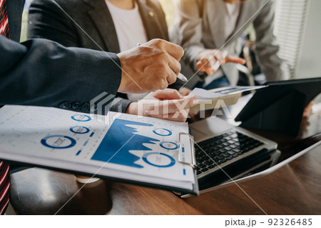Business documents on office table with smart phone and laptop and two colleagues discussing data in the background Business documents on office table with smart phone and laptop and two colleagues discussing data in the background 92326485