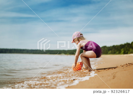 cute little girl playing with rubber ball in sea 92326617