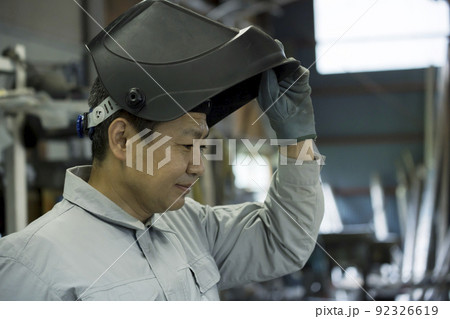 工場内で溶接マスクをする作業員男性 工場内で溶接マスクをする作業員男性 92326619