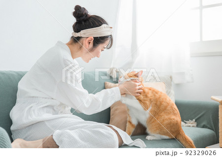 家で猫を抱っこする日本人女性（ペット・飼い主） 92329026