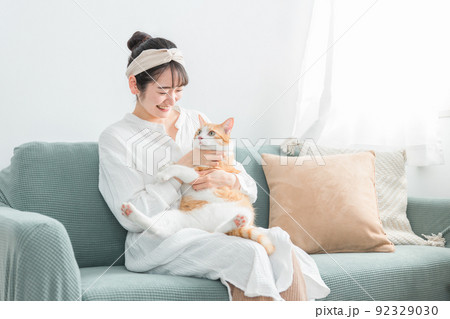 家で猫を抱っこする日本人女性（ペット・飼い主） 92329030
