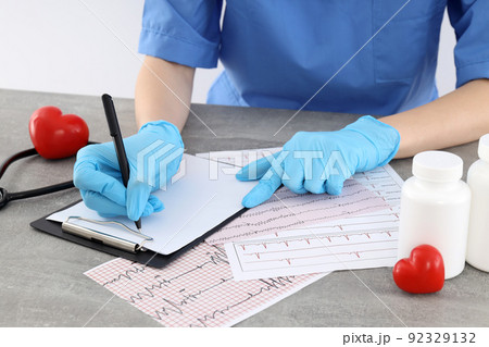 Female doctor write prescription into clipboard on table 92329132