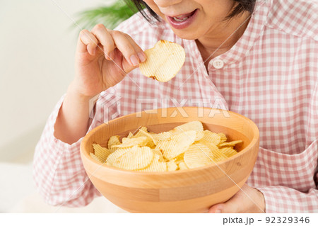 寝室でポテトチップスを食べるミドル女性 寝室でポテトチップスを食べるミドル女性 92329346