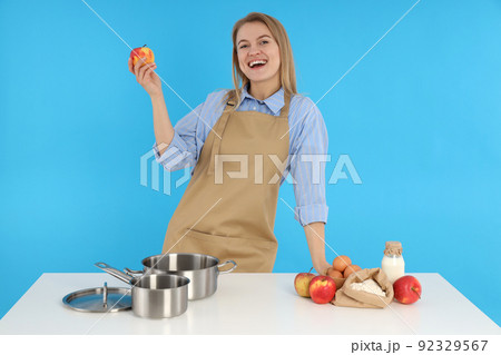 Concept of cooking with young woman on blue background Concept of cooking with young woman on blue background 92329567