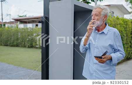 An old senior man smoking cigarette outside, smoke addiction, bad habbit. An old senior man smoking cigarette outside, smoke addiction, bad habbit. 92330152