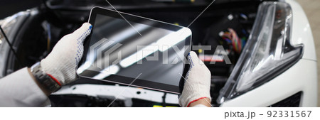 Mechanic use tablet device with black screen in front of car. Mechanic use tablet device with black screen in front of car. 92331567
