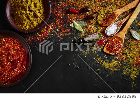 Set of indian spices on black background - green cardamom, turmeric powder, coriander seeds, cumin, and chili, top view Set of indian spices on black background - green cardamom, turmeric powder, coriander seeds, cumin, and chili, top view 92332898