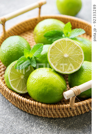 Green  Limes with fresh mint leaves on wicker tray 92333289