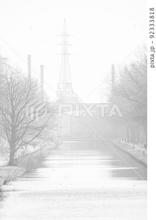 High key Black and white industrial landscape with power lines, trees, road and a canal or waterway High key Black and white industrial landscape with power lines, trees, road and a canal or waterway 92333818