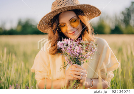 Portrait of happy woman in straw hat in fresh green wheat field. Grass background. Amazing nature 92334074