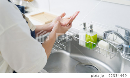 皿洗いをして手が荒れる女性（家事・主婦・キッチン） 92334449