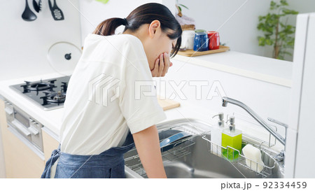 妊娠してつわりに苦しむ料理中の女性（家事・主婦・キッチン） 92334459