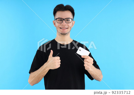 Attractive guy with credit card on blue background Attractive guy with credit card on blue background 92335712
