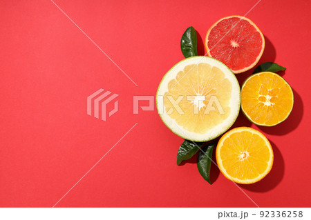 Citrus fruits halves with leaves on red background 92336258