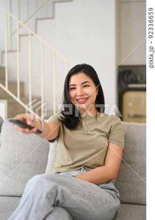 Relaxed asian woman watching tv, enjoying leisure weekend time at home Relaxed asian woman watching tv, enjoying leisure weekend time at home 92336659