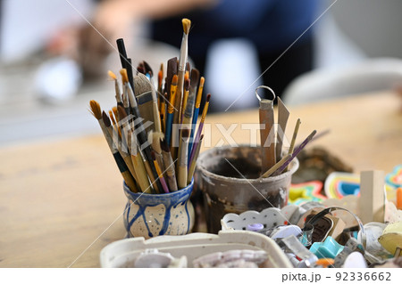 Ceramics making equipment with paint brushes, pottery shaping tools on wooden table in creative studio 92336662